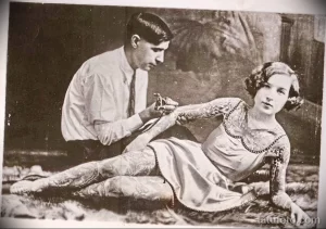 Старинная фотография женщины с обширными татуировками на теле, выполненными в традиционном стиле.