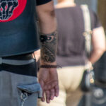 байкер в жилетке из кожи с татуировкой браслет Маори узором внизу правой руки32