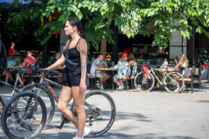 Фото тату на предплечье девушки, идущей с велосипедом по улице. Рисунок татуировки выполнен в темных тонах, детализированный эскиз.