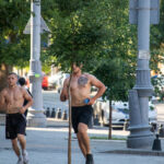два парня с голым торсом и татуировками на теле бегают в центре города34