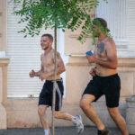 два парня с голым торсом и татуировками на теле бегают в центре города4848