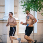 два парня с голым торсом и татуировками на теле бегают в центре города4949