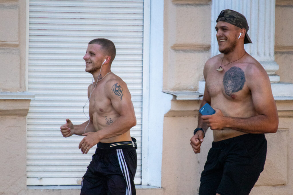 два парня с голым торсом и татуировками на теле бегают в центре города5151