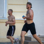 два парня с голым торсом и татуировками на теле бегают в центре города5454