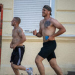 два парня с голым торсом и татуировками на теле бегают в центре города5555