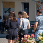 Фото тату на руке, представляющее собой рукав с изображением городских зданий, уличных фонарей и других элементов, выполненных в серо-черной гамме с добавлением ярких цветовых акцентов.