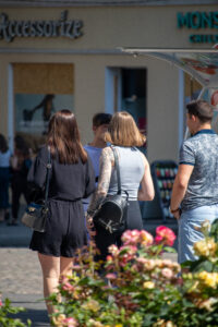Фото тату на руке, представляющее собой рукав с изображением городских зданий, уличных фонарей и других элементов, выполненных в серо-черной гамме с добавлением ярких цветовых акцентов.