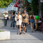Фото пары, идущей по улице. У девушки есть татуировка на ноге, а у парня – на руке. Татуировки выполнены в разных стилях и дополняют друг друга.