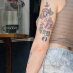 девушка с олдскул татуировками цветов якоря и портретов на левой руке 7