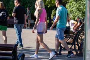 Фото тату: Девушка с яркой японской татуировкой на руке, изображающей гейшу и цветы, идущая по улице.