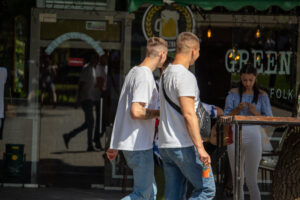 Фото мужчины с татуировкой на руке, стоящего возле паба. Видна часть татуировки с изображением, возможно, черепа.