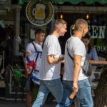 Фото мужчины с татуировкой на руке, стоящего возле паба. Видна часть татуировки с изображением, возможно, черепа.