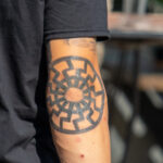 молодой парень с татуировкой Славянский символ солнце на правом локте00