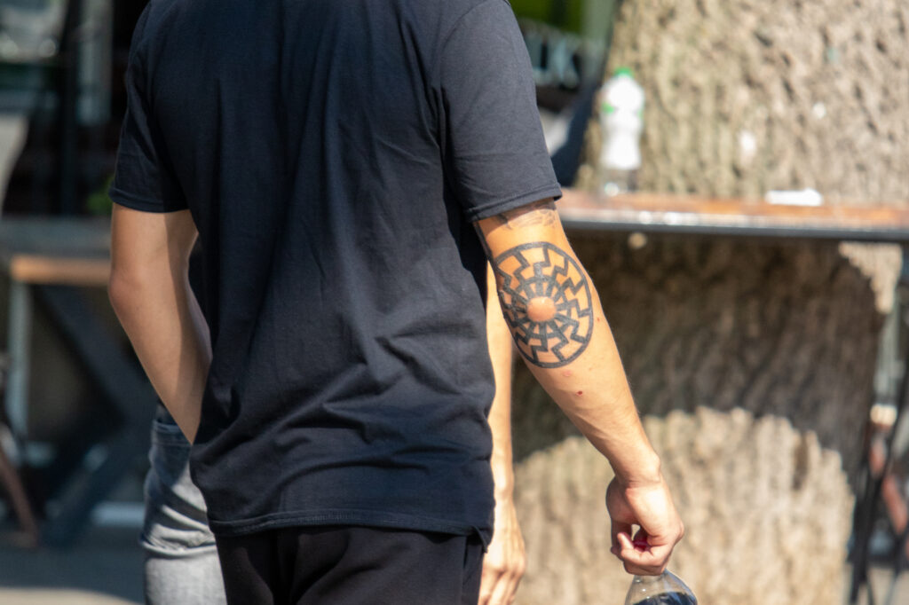 молодой парень с татуировкой Славянский символ солнце на правом локте59