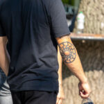 молодой парень с татуировкой Славянский символ солнце на правом локте59