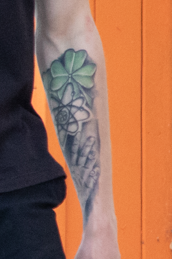молодой парень с татуировкой клевер символ атома и ладонь на левой руке48