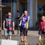 Фото тату на руке мужчины, изображающее японский стиль с волнами и цветами, на фоне городской улицы.