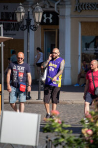 Фото тату на руке мужчины, изображающее японский стиль с волнами и цветами, на фоне городской улицы.