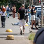 Фото тату на икре мужчины, идущего по улице. Видна татуировка с изображением головы медведя в реалистичном стиле.