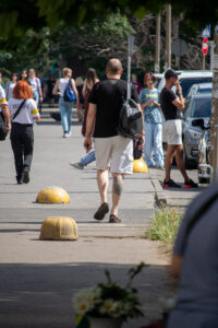 Фото тату на икре мужчины, идущего по улице. Видна татуировка с изображением головы медведя в реалистичном стиле.