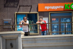 Фото двух мужчин с татуировками на руках, стоящих на балконе. Видны татуировки на руках, белые и красные футболки.