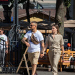 Фото мужчины с татуировкой на руке и женщины, идущих по улице. Мужчина держит в руке сумку через плечо.