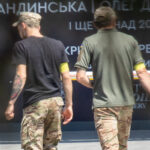 Фотография двух мужчин с татуировками на руках, одетых в военную форму. Видны татуировки на предплечьях и бицепсах.