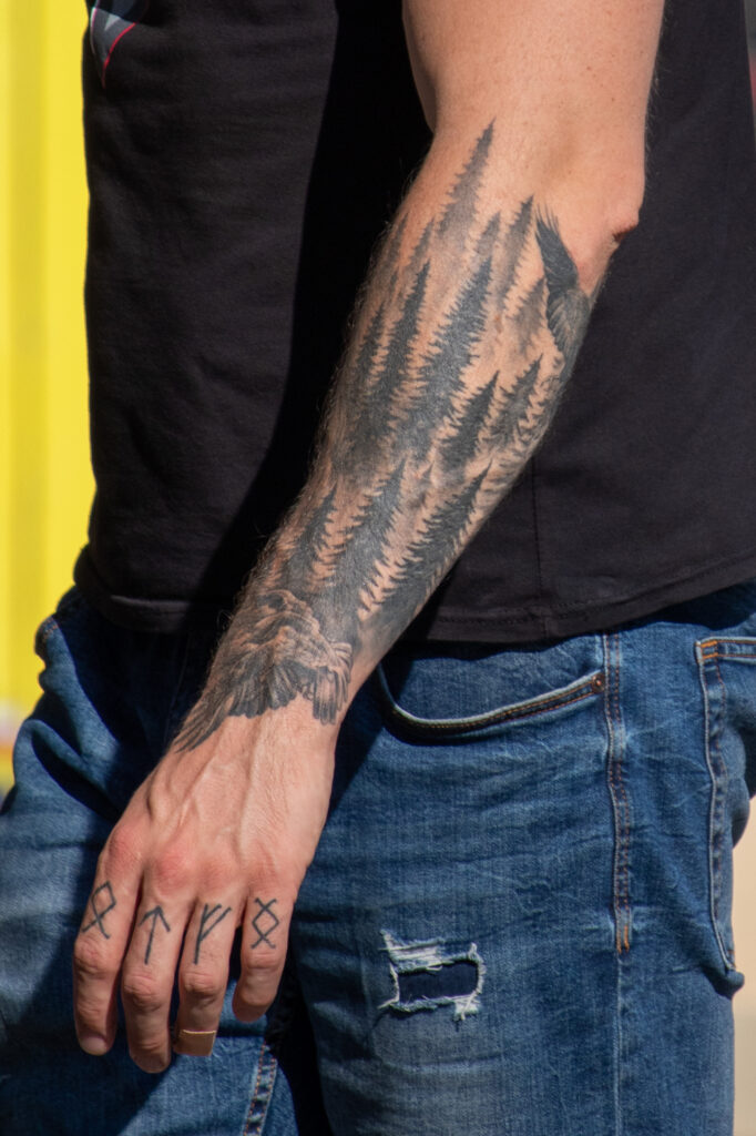 парень с татуировками Лиса и рунами на левой руке32