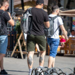 Фотография мужчины, идущего по улице, у которого видны татуировки на икрах. Татуировки выполнены в темных тонах и имеют сложный дизайн.