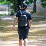 Фото тату на руке мужчины, идущего по парковой аллее. Вид сзади, татуировка в стиле традишнл.
