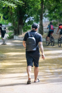 Фото мужчины с татуировками на руках, идущего по улице. Видны детализированные рисунки на предплечьях.