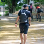 Фото мужчины с татуировками на руках, идущего по улице. Видны детализированные рисунки на предплечьях.