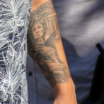 парень с татуировками на руках монашка с крестом во лбу а также портрет Цезаряbm