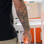 парень с татуировкой из цветов и листьев на руке и ноге 4