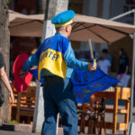 пожилой мужчина в одежде Супергероя стилизованное под флаг Украины и надписью сделай что-нибудь полезное для Украины4444
