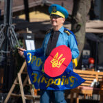 Фото мужчины в костюме казака с саблей и щитом. Яркий образ с украинской символикой.
