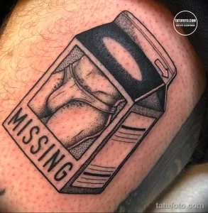 Фото татуировки в стиле Old School с изображением женской фигуры в рамке с надписью 'Missing'. Татуировка выполнена в черно-белой гамме с использованием четких контуров и ярких акцентов.