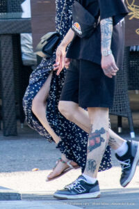 Фото тату на лодыжке: реалистичный рисунок пистолета, обвитого цветами, выполненный в черно-серых тонах. Детализированный эскиз татуировки.