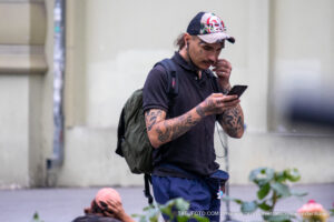 Фотография мужчины с множеством татуировок на руках, шее и лице. На голове у него кепка с черепом.