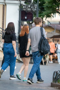 Фото тату: Мужчина с татуировкой на левой руке идет по улице. Татуировка представляет собой схематичное изображение, выполненное в черном цвете.