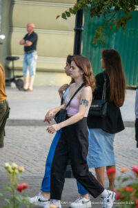 Фото татуировки бабочки на плече девушки в розовой майке. Детализированный рисунок с прорисовкой крыльев.