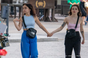 Фотография двух девушек с небольшими татуировками на руках. Минималистичные рисунки, выполненные в черном цвете. Уличная фотография тату.