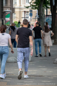 Фотография мужчины и женщины, идущих по улице. У мужчины на руке видна татуировка с изображением розы и надписи.