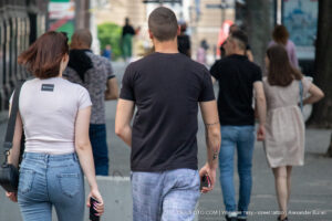 Фотография мужчины и женщины, идущих по улице. У мужчины на руке видна татуировка с изображением розы и надписи.