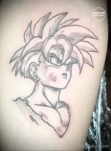 Фото татуировки персонажа Гоку из аниме Dragon Ball на руке. Черно-белый рисунок в стиле аниме. Детализированное изображение лица и волос.