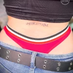 Фото татуировки надписью "UNFORGETTABLE" на спине. Простой шрифт в черном цвете. Мотивационный эскиз для тех, кто ценит воспоминания.