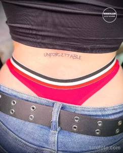 Фото татуировки надписью "UNFORGETTABLE" на спине. Простой шрифт в черном цвете. Мотивационный эскиз для тех, кто ценит воспоминания.