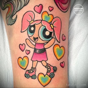 Цветное фото тату с изображением Пузырь из Powerpuff Girls на руке. Яркий и детализированный рисунок в стиле мультфильмов с окружением из сердец.
