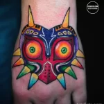 Фото тату маски Майохи из The Legend of Zelda на стопе. Яркий рисунок с использованием различных цветов. Эскиз тату для фанатов игр.