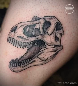 Фото тату черепа динозавра в стиле blackwork. Детализированный рисунок татуировки с использованием черных тонов. Отличный выбор для поклонников древних ящеров.